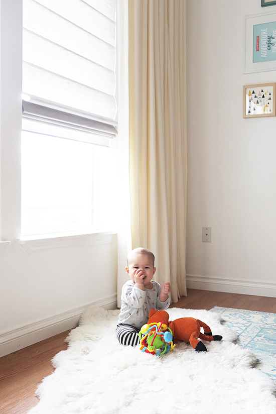 Baby sitting next to window with drapes